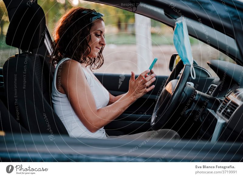 young woman in a car. Protective mask hanging from rear mirror. Travel and new normal concept protective mask driving corona virus travel pollen protection