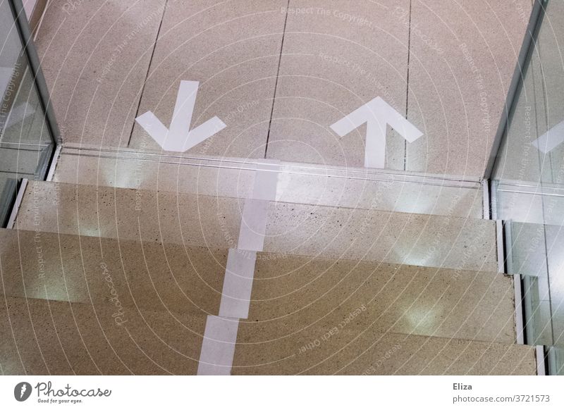 Directional arrows on the floor in front of a staircase. Setting the direction of movement in Corona times. Arrow running direction Stairs corona