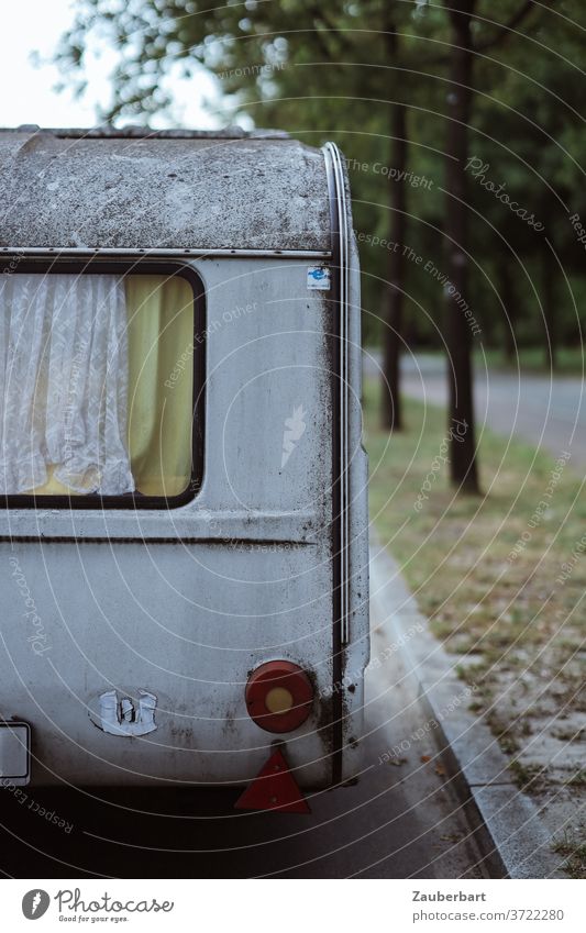 Old caravan with window and curtain at the roadside Caravan Roadside Window Curtain Yellow Weathered Street vacation Camping vanlife switch off turned off