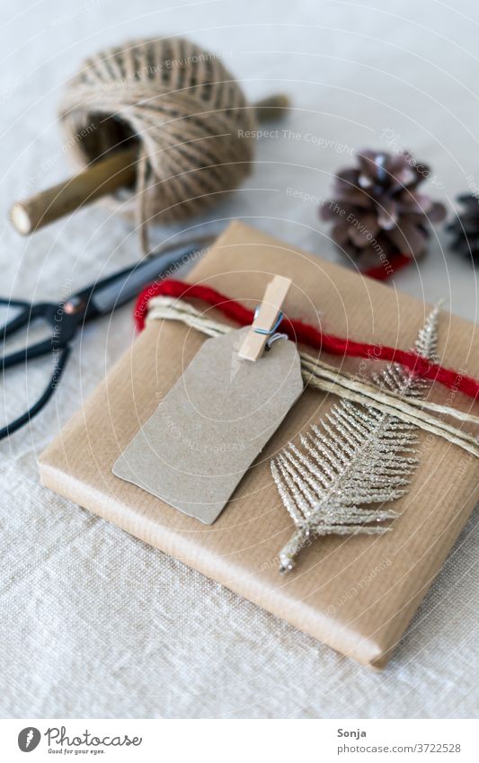 Gift christmassy wrapped on a linen tablecloth. Christmas & Advent Packaging Feasts & Celebrations White Studio shot Decoration Ornament Band Red Linen cloth