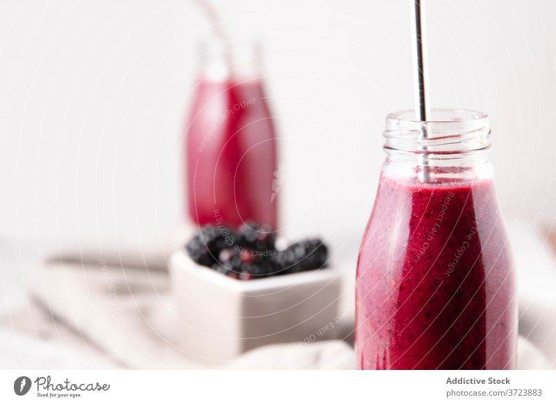 Crop shot of a glass bottle containing pink homemade berry smoothie, with a metal straw. Berry smoothie Bottle Color Drink Food and drink Fruits Gastronomy