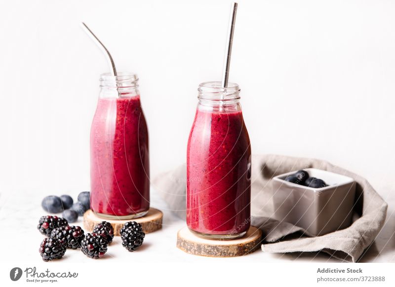 Berry smoothie in glass bottles with reusable metal straws. Front shot with white background. Bottle Color Drink Food and drink Fruits Gastronomy Glass bottle
