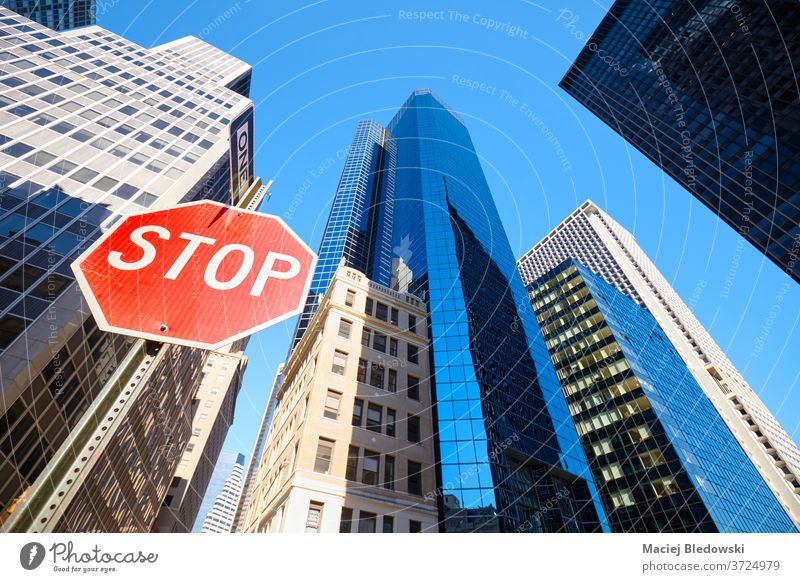 Looking up at stop sign on a street of New York City, USA. city look up nyc office building business Manhattan skyscraper warning traffic sign window red