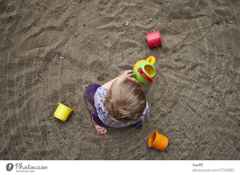 Toddler playing in the sand I Sand Sandpit Playing Playground Infancy Exterior shot Children's game Bird's-eye view