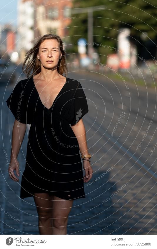 the woman is walking, her gaze directed at the camera, elegantly and confidently down the street. Woman Feminine Young woman 18 - 30 years long hair