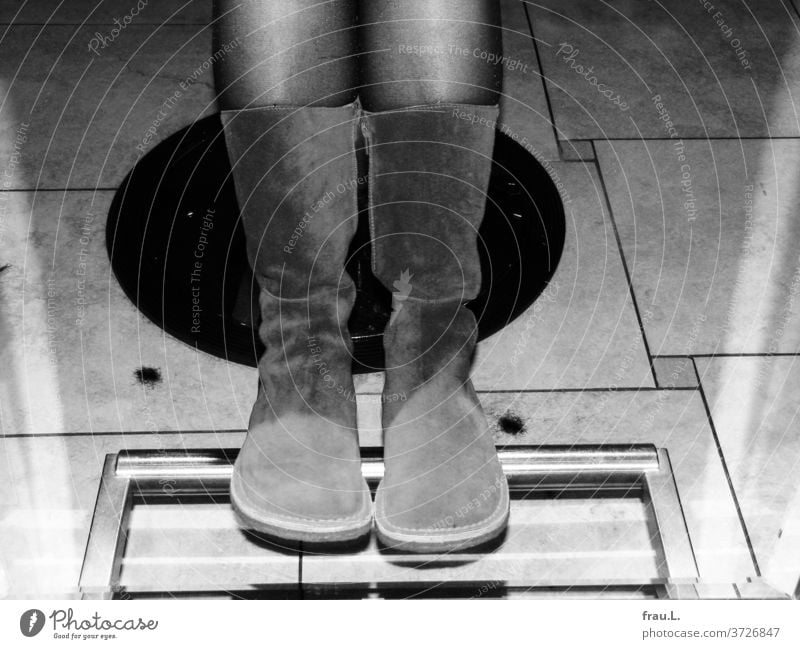 A pair of legs and boots admire each other in the full body mirror of the hairdressing salon. Hair Stylist Hairdresser Mirror floor tiles Tuft of hair