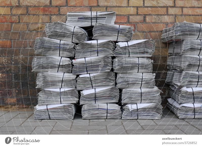 newspaper stack on street pile bundle bunch press media heap delivery piled stacked bundled bunched tabloid nobody sidewalk background footpath pavement