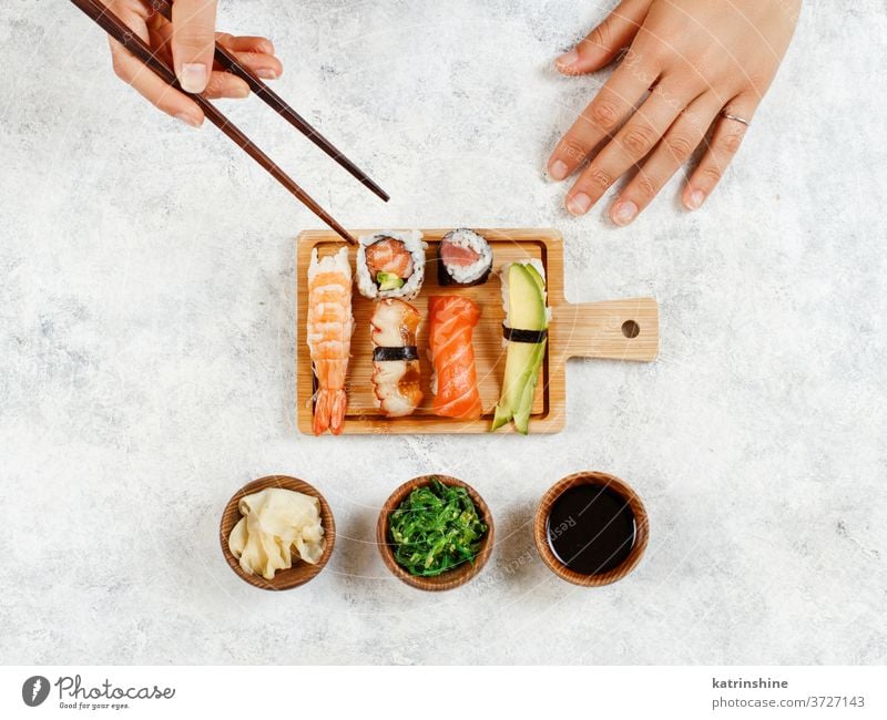 Top view of hand taking roll with chopsticks sushi ready to eat eating Sashimi Rolls sushi bar dinning Japanese Culture Seafood plate top view Asian Prawn Tuna