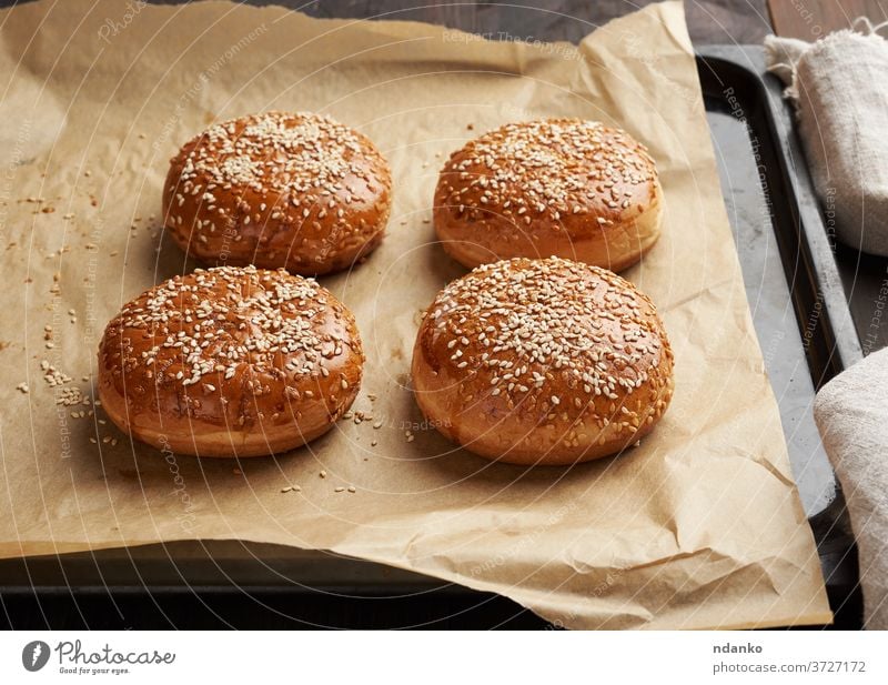 baked sesame buns on brown parchment paper, ingredient for a hamburger cheeseburger classic closeup crust delicious bakery bread breakfast eating fastfood flour