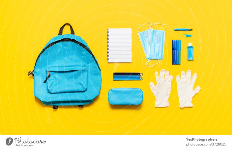 School supplies and backpack top view. Back to school in pandemic with protective masks back to school background blue concept copy space corona coronavirus