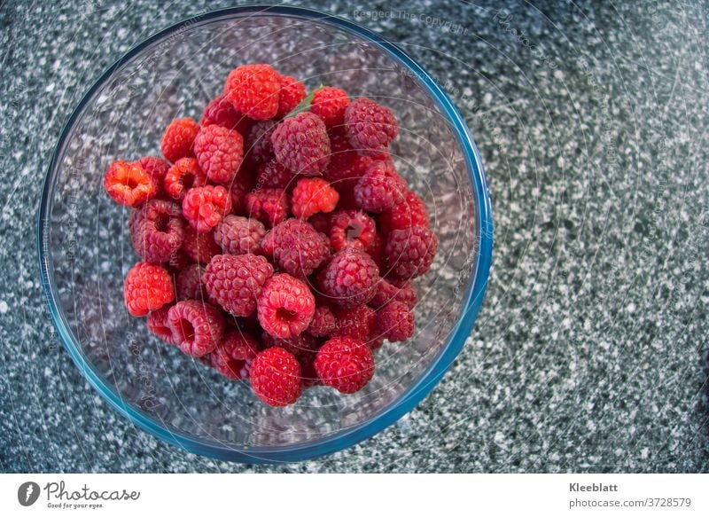 Raspberries freshly harvested from the organic garden arranged in a glass bowl waiting to be eaten Fresh Organic produce Delicious Red Glass bowl Grey ground