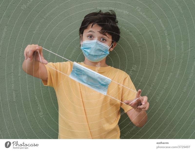 kid wearing medical mask holding a protective medical mask coronavirus epidemic pandemic quarantine child covid-19 symptom medicine health positive test