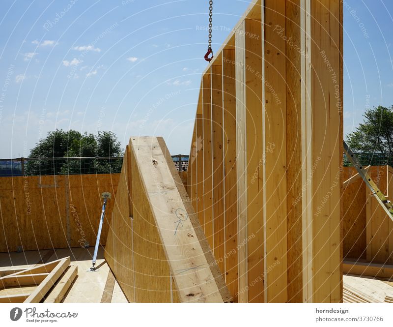 Timber construction site, a house wall is hanging on the crane Wooden house carpentry timber construction Construction site wood Colour photo Exterior shot