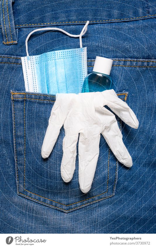 New normal in pandemic concept. Medical mask, hand sanitizer, and gloves in jeans back pocket avoidance back-pocket blue care close-up corona coronavirus