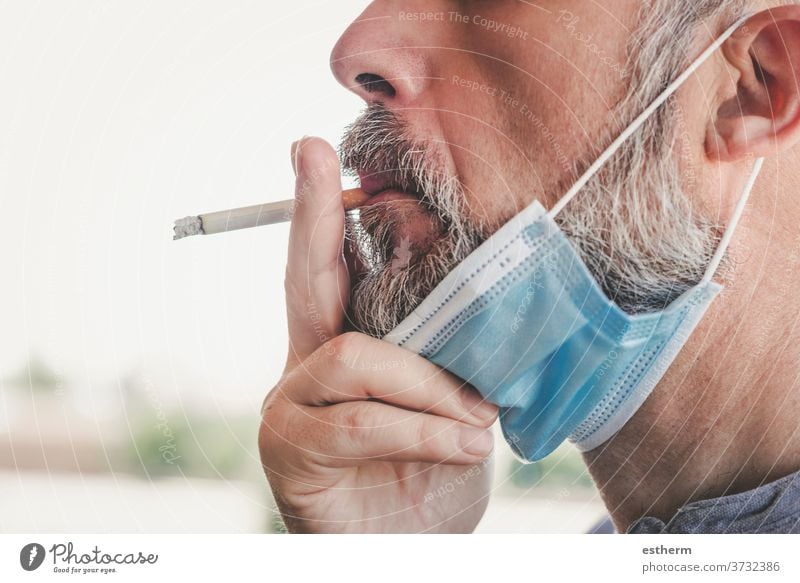 covid-19,man with medical mask smoking a cigarette at the street coronavirus 2019-ncov unhealthy smoke epidemic prohibition cancer protection clampdown habit