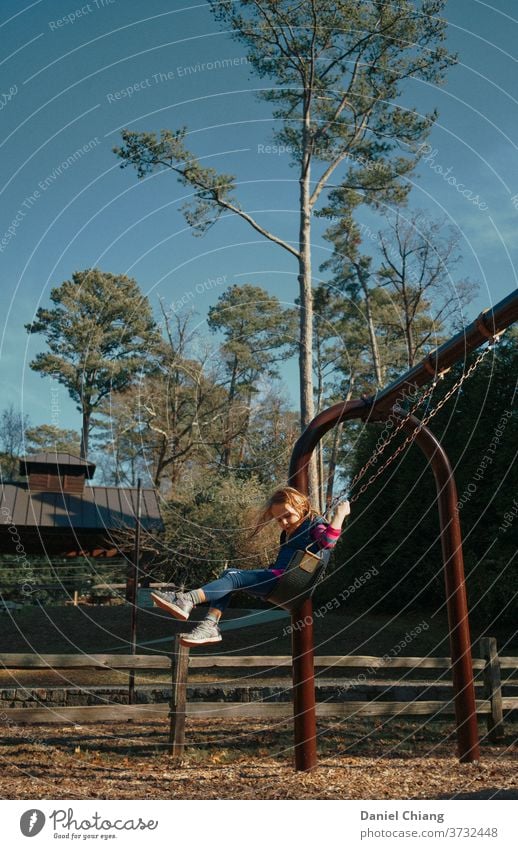 Portrait of a happy, laughing 8 year old girl with long blond hair playing  on the slide - a Royalty Free Stock Photo from Photocase