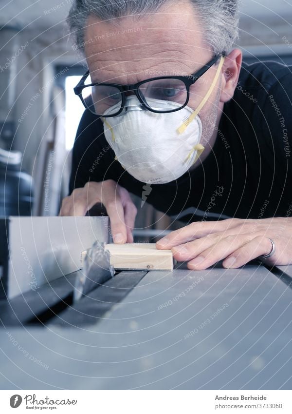 Man with a dust mask and goggles working on a circular saw tools machinery handyman worker manufacture activity protective protection occupational safety