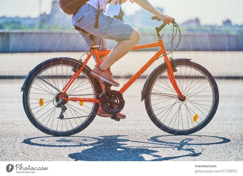 Young woman riding a bicycle on the city street Woman girl Bicycle City Ride Street cyclists Reporter Badge Camera Backpack Sunlight Weather warm Speed