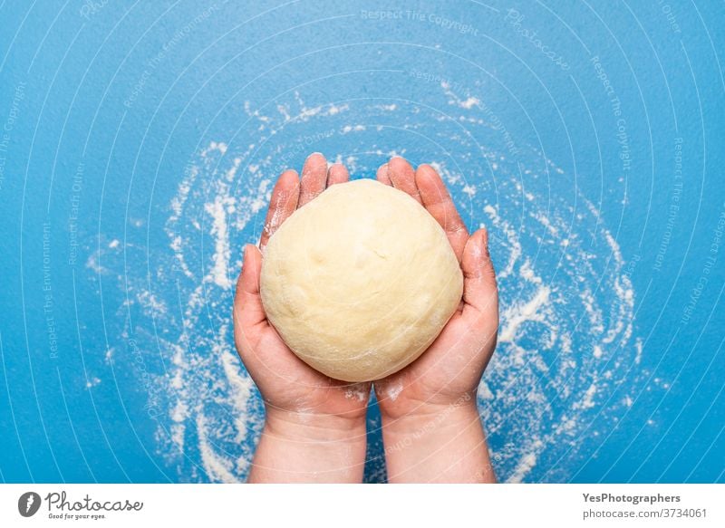 Bread dough hold in hand over a blue table. Uncooked dough. Baking at home background bake bakery baking bread bread dough buns concept cooking copy space