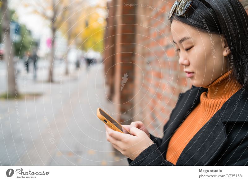 Asian woman using her mobile phone. street smartphone asian people urban cellphone female text young sms message outdoor adult online internet use japanse
