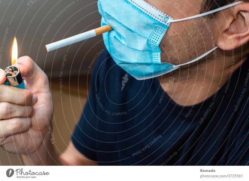 Young man with mask lighting a cigarette. Coronavirus funny concept coronavirus covid crazy strange rare new normal idiot stupid person silly joke young party
