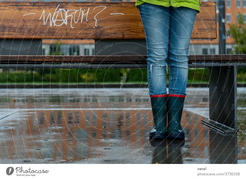 Seat band with writing "why?" in the rain with children legs in rubber boots Colour photo Exterior shot Authentic Freedom Day Street Small Town
