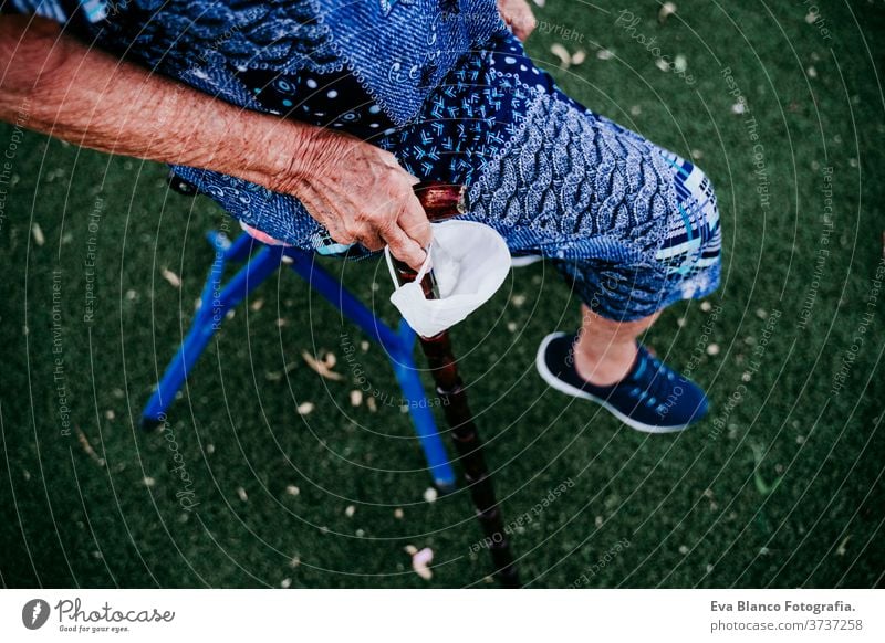 close up of old lady hands holding a stick and protective mask outdoors. new normal old woman portrait elderly home white hair grey hair mental solitude