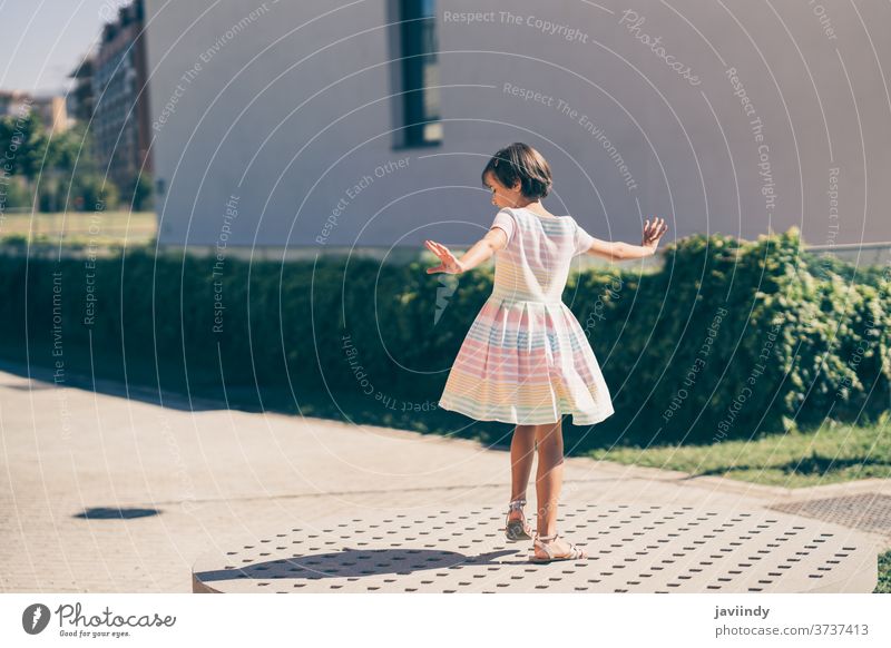 Happy 9-year-old girl in a pretty dress playing kid little child urban summer cute city female young style childhood fashion street beautiful lifestyle portrait