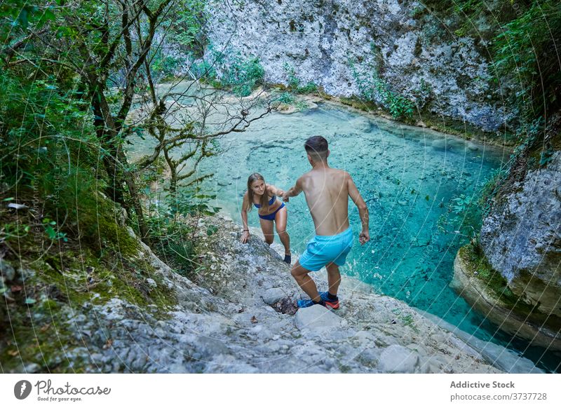 Couple of tourists near lake in mountains hike traveler climb couple adventure tourism help turquoise bikini swimwear paradise girlfriend boyfriend highland