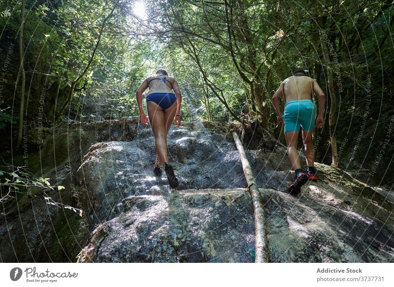 Traveling couple climbing cliff in summer rock travel adventure rocky forest slope swimwear holiday activity freedom nature vacation together tourism trip