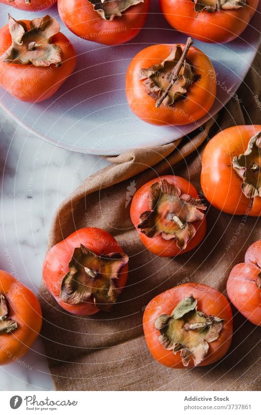 Ripe persimmons on plate in kitchen fruit sweet top view pile fresh vitamin diet nutrition nutrient delicious bright table healthy heap natural food