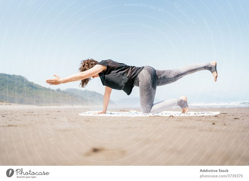 Slim woman doing yoga pose on the beach sea practice asana balance calm seashore harmony wellness lifestyle flexible eyes closed female nature vitality activity
