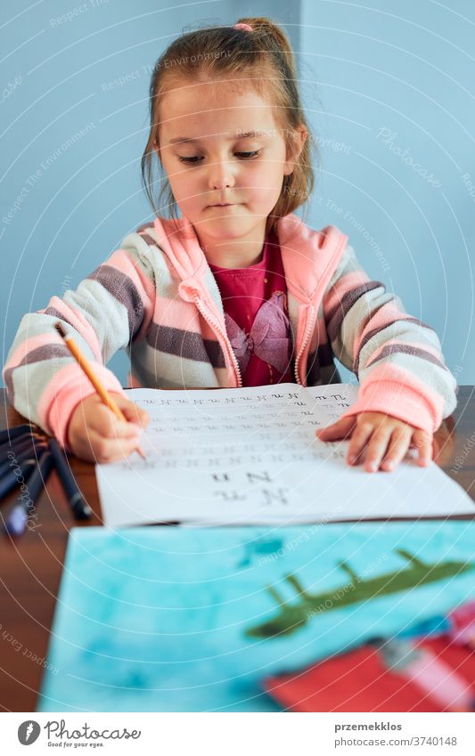 Little girl preschooler learning to write letters at school. Kid writing letters doing a school work. Concept of early education attention caucasian child