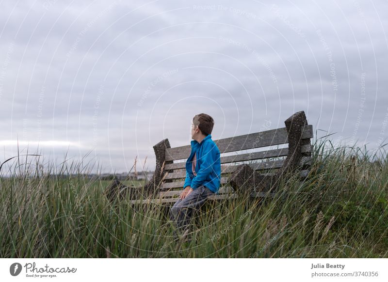 boy on a bench at the seaside ocean ocean view cloudy clouds solitude alone grass beach grass vacation pacific ocean Oregon United States summer cool reeds
