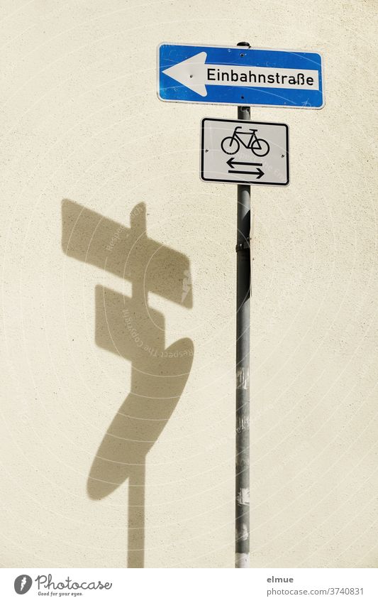 Shadow play of a three-part traffic sign "one-way street" / "cyclist" / ? Road sign One-way street cycle path Traffic infrastructure Signs and labeling