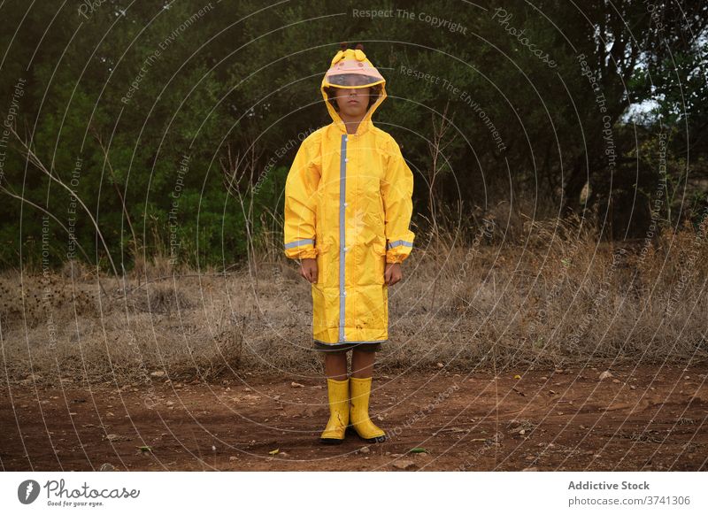 Portrait of a boy in a yellow hooded raincoat and rain boots standing outdoors schoolboy hide wear protective way comfortable trendy security stylish wet