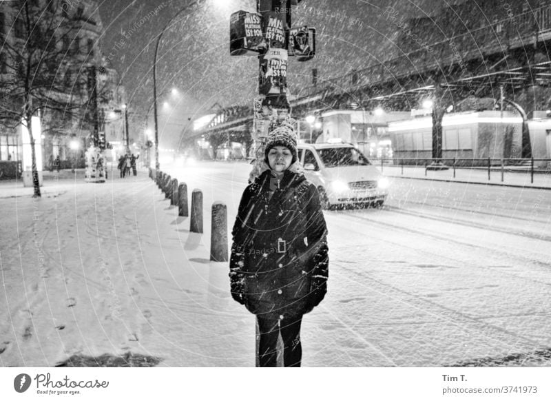 a woman stands at a traffic light at night when it is snowing Woman Winter Berlin Night Prenzlauer Berg Schönhauser Allee bnw Snow Snowfall Downtown