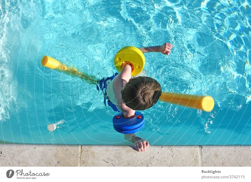 Top view of little boy floating in swimming pool with floats and arm bands vacation holiday kid happy lifestyle young healthy recreation active play above aids
