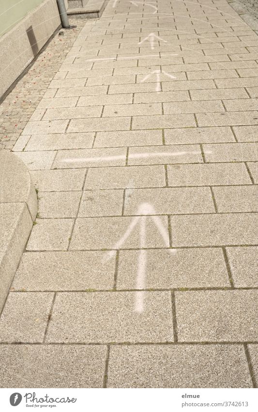 white arrows and lines on the sidewalk illustrate the distance control during corona gap Arrow Distance control off coronavirus Footpath risk of contagion