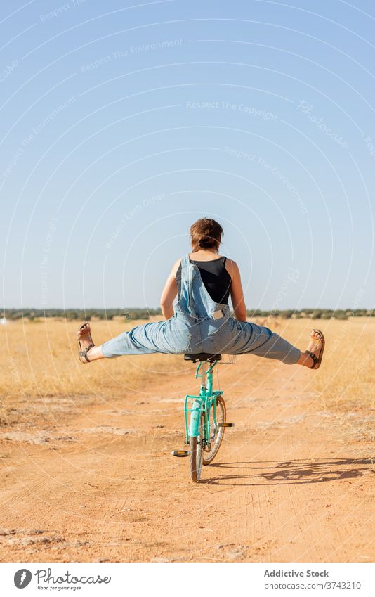 Woman on bicycle in rural area woman road sand sunlight overall bike countryside happy serene female sunglasses denim summer nature relax casual carefree