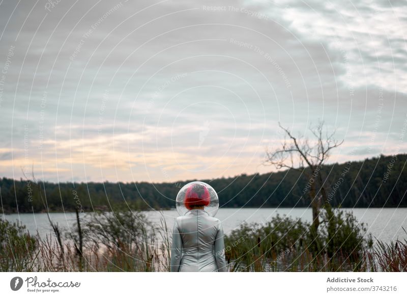 Woman in astronautic suit walking to water woman futuristic space helmet river nature cosmonaut concept female silver future fantasy science explore planet