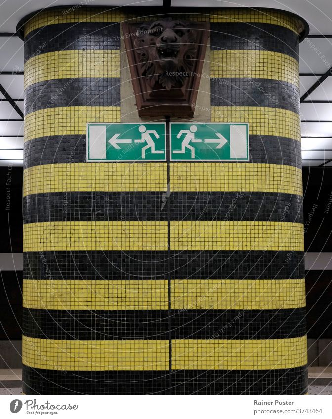 Two exit signs in a subway station pointing into opposite directions arrow arrow symbol background dark decide decision flee information pattern subway exit