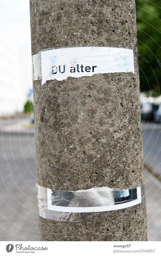 Remains of an A4 sheet of paper glued to a concrete pillar with the title "You old one" leave room for thought games Notice Paper remnants piers lamp post