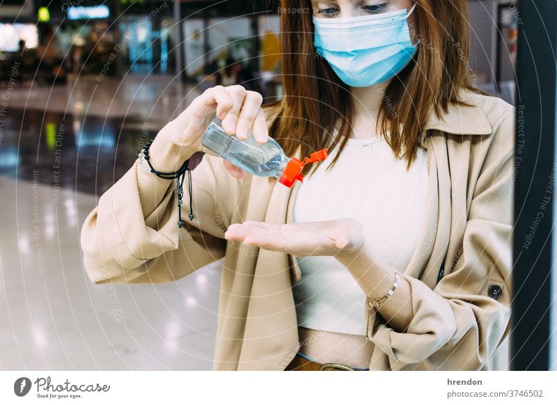 a woman wearing a face mask and using hydro-alcoholic gel to disinfect her hands at the train station traveling voyage virus coronavirus epidemic pandemic