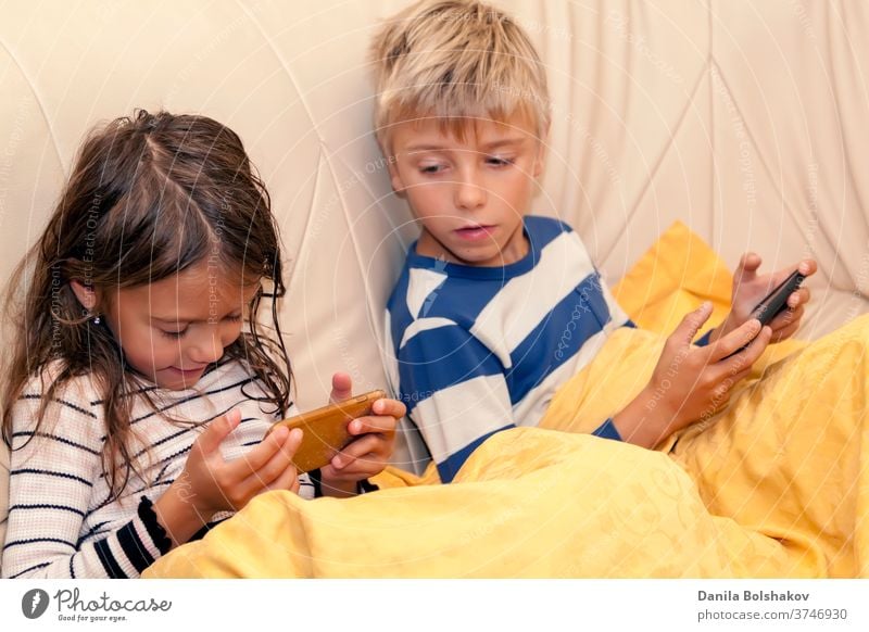 Little girl and boy playing game or watching something on mobile smart phone cartoons mobile phone resting watching cartoons surfing the net connection