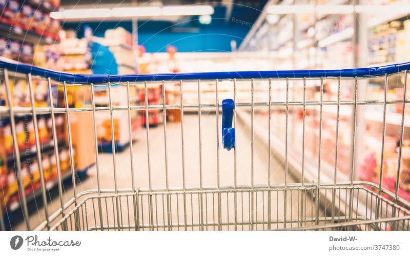 Shopping trolleys in the supermarket between shelves with food Shopping Trolley Food Supermarket business Customer consumer Store premises void Empty