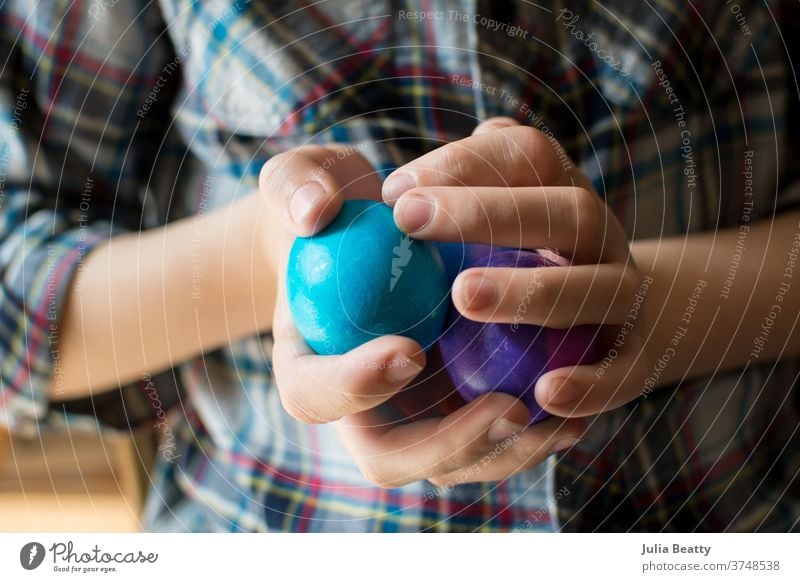 Child wearing plaid shirt holding multicolored Easter Eggs Easter egg Spring Decoration Multicoloured Feasts & Celebrations Tradition hands eggs fingernails
