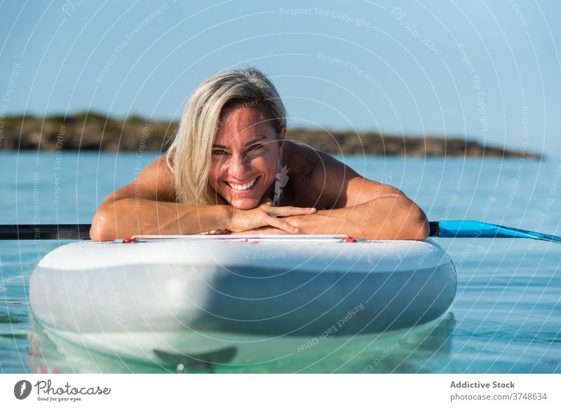 Cheerful woman relaxing on paddleboard in sea surfer summer surfboard rest training female lying water sup board fit slim ocean sunny activity sport exercise