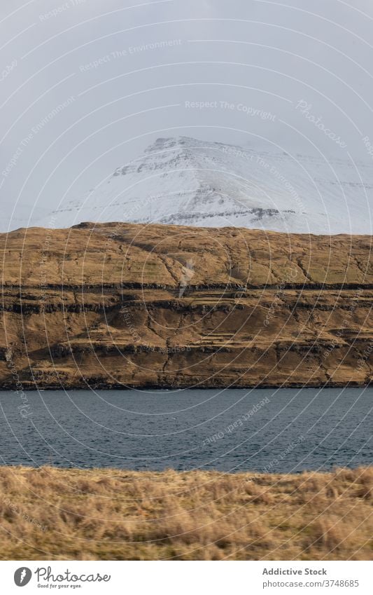 Rocky cliff near sea on Faroe Islands rock seascape winter snow season cold steep terrain faroe islands rocky scenery majestic coast shore water sky calm