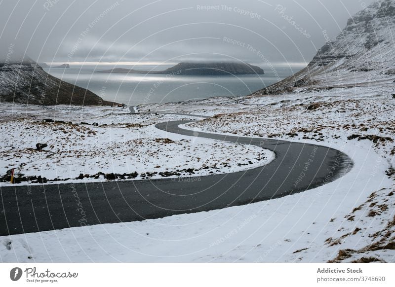Curvy road running through snowy valley winter country empty curve desert north severe terrain cold field hill ice mountain landscape nature travel nordic path